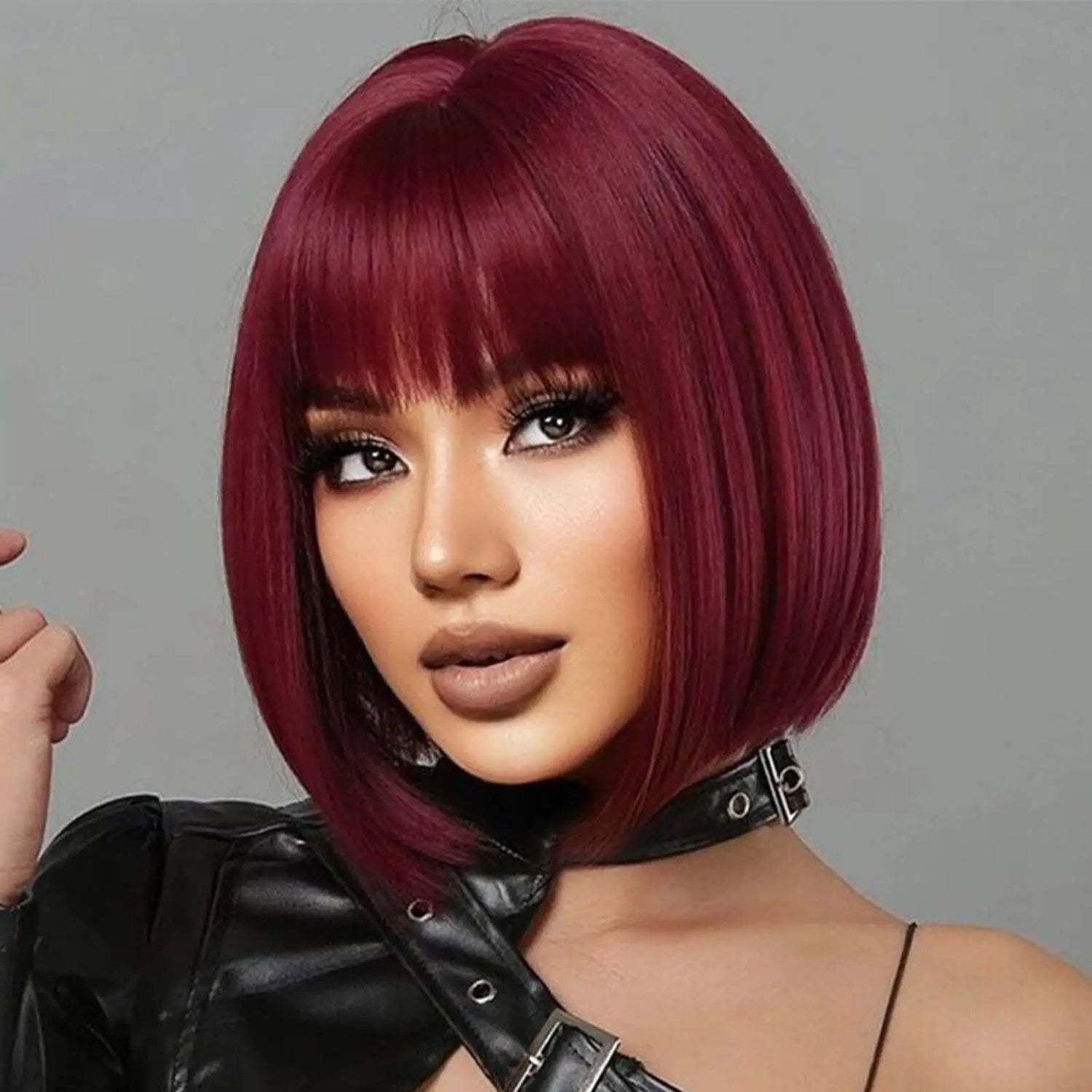 Woman with a stylish burgundy bob wig against a gray background