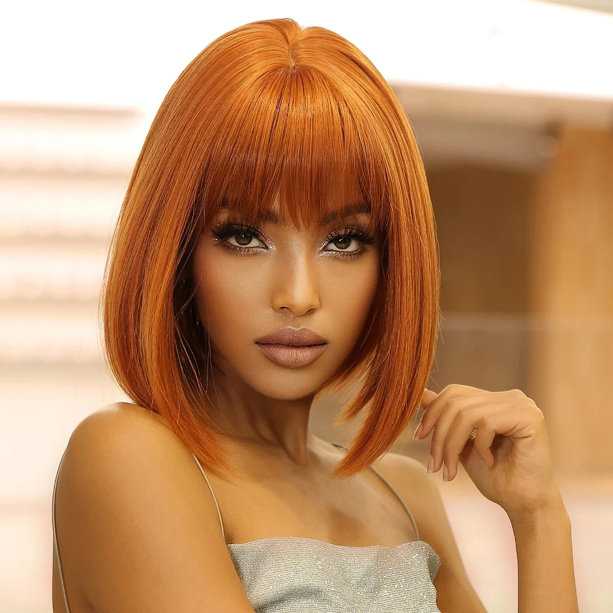 Woman with orange hair and a silver top against a blurred background