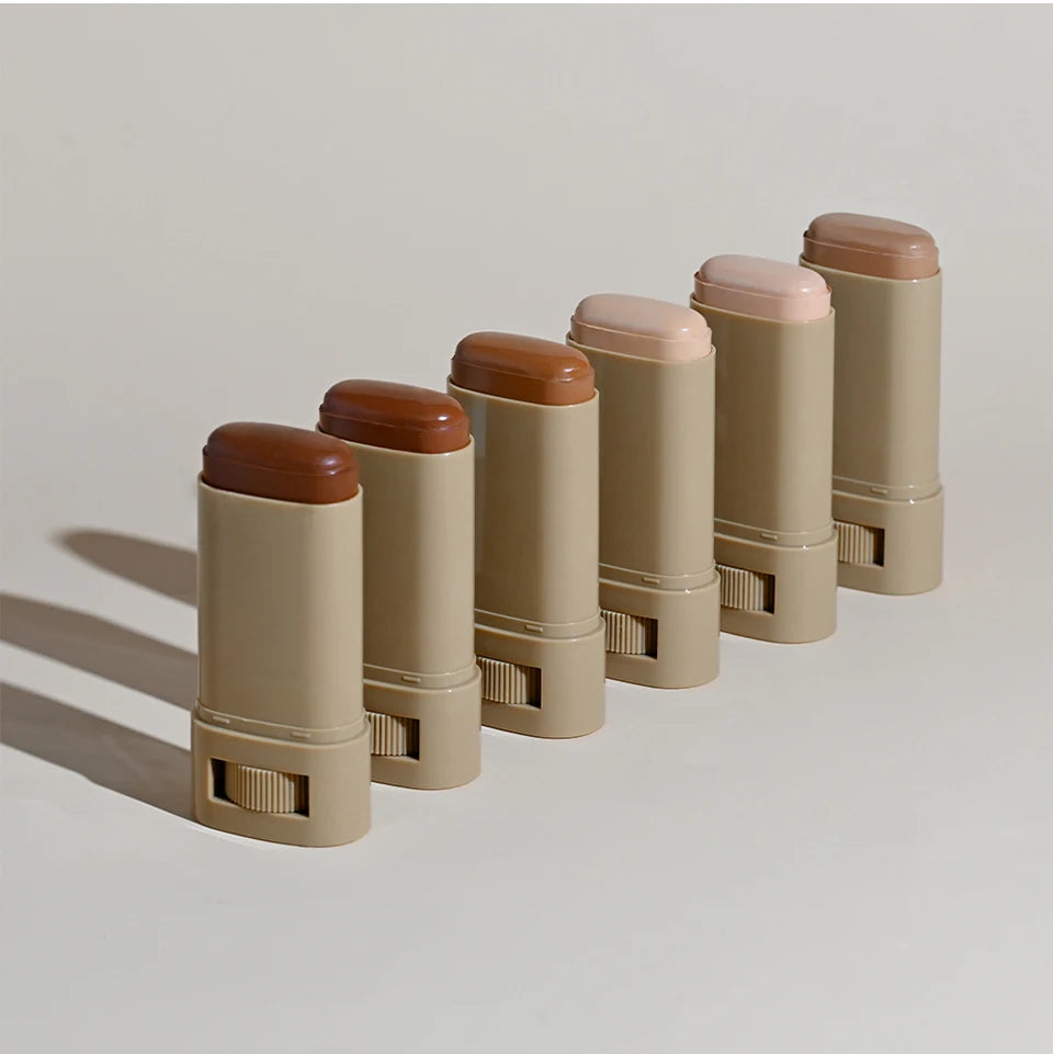 Set of beige makeup sticks with brown caps on a light gray background